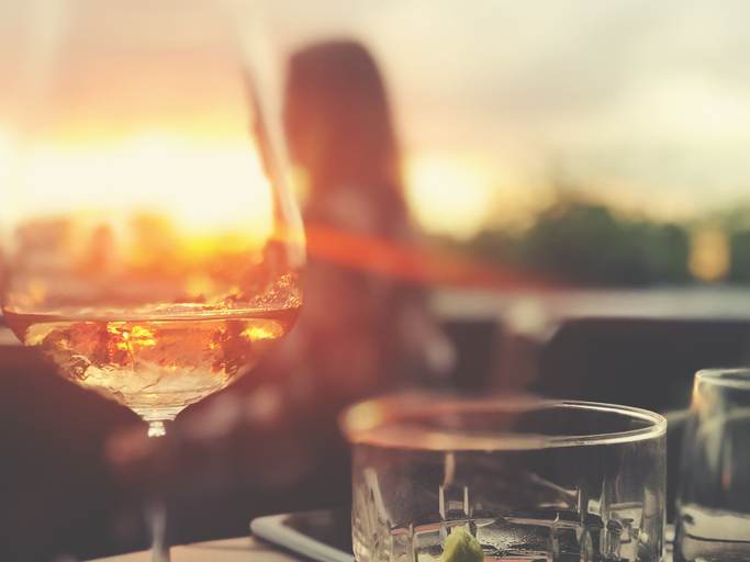 Wine and cocktails on a table at a bar.