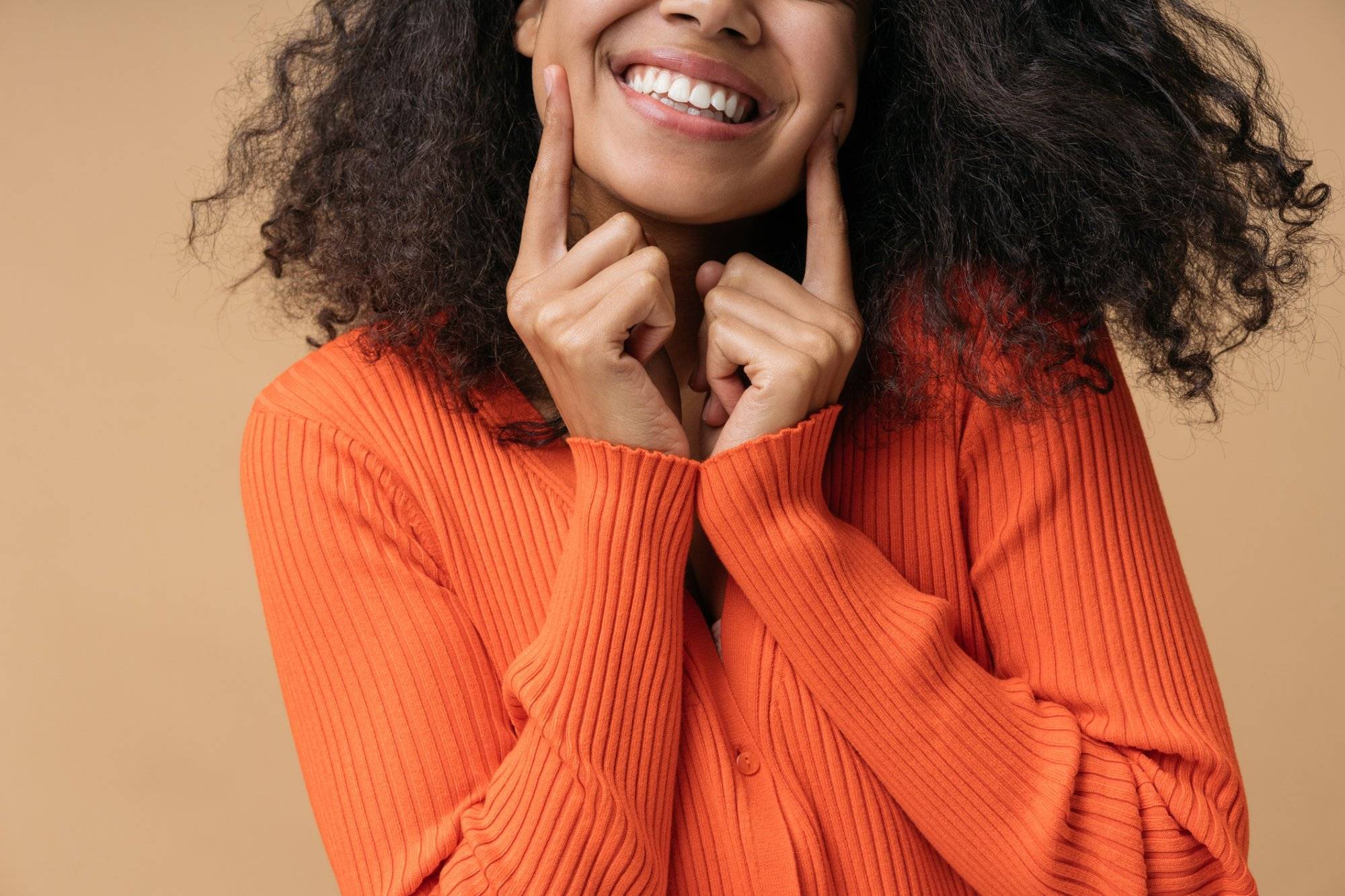 Close up portrait of young happy African American woman pointing finger on white teeth isolated on background. Health care, dental treatment concept